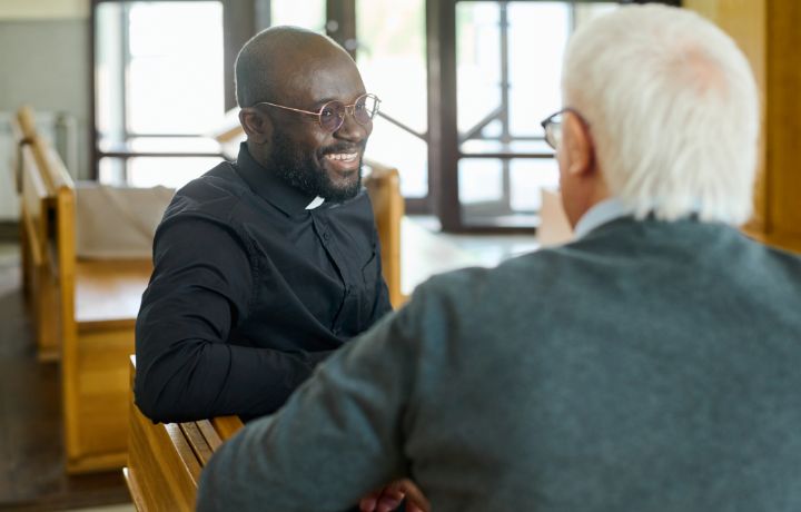 Grandfather talking to a Catholic priest in a church.